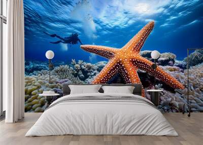 a starfish on a coral reef in the ocean with a blue background and a coral reef in the foreground with a diver in the background and a blue sky with a few clouds.  Wall mural